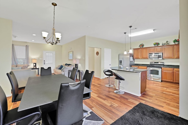 dining area with light wood-type flooring and a notable chandelier