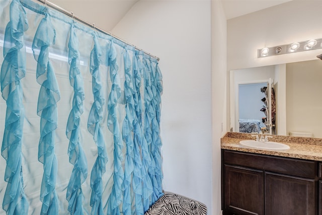 bathroom with a shower with curtain, vanity, and vaulted ceiling