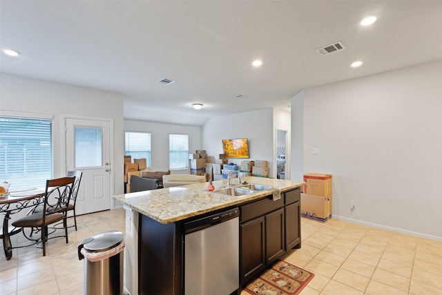 kitchen with light stone counters, dishwasher, sink, a kitchen island with sink, and dark brown cabinets