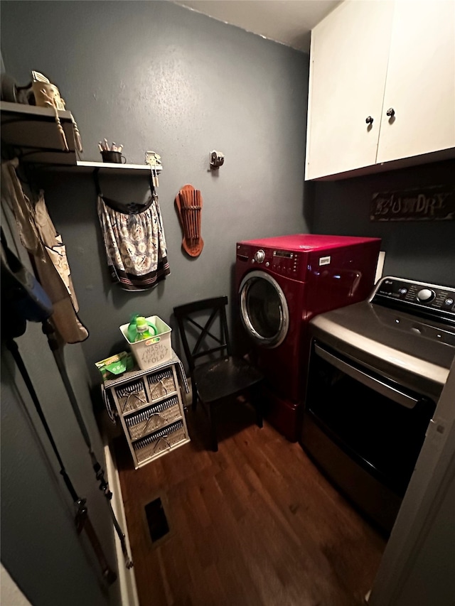 laundry area with washing machine and dryer, cabinets, and hardwood / wood-style floors