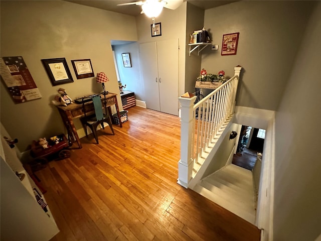 stairway with ceiling fan and wood-type flooring