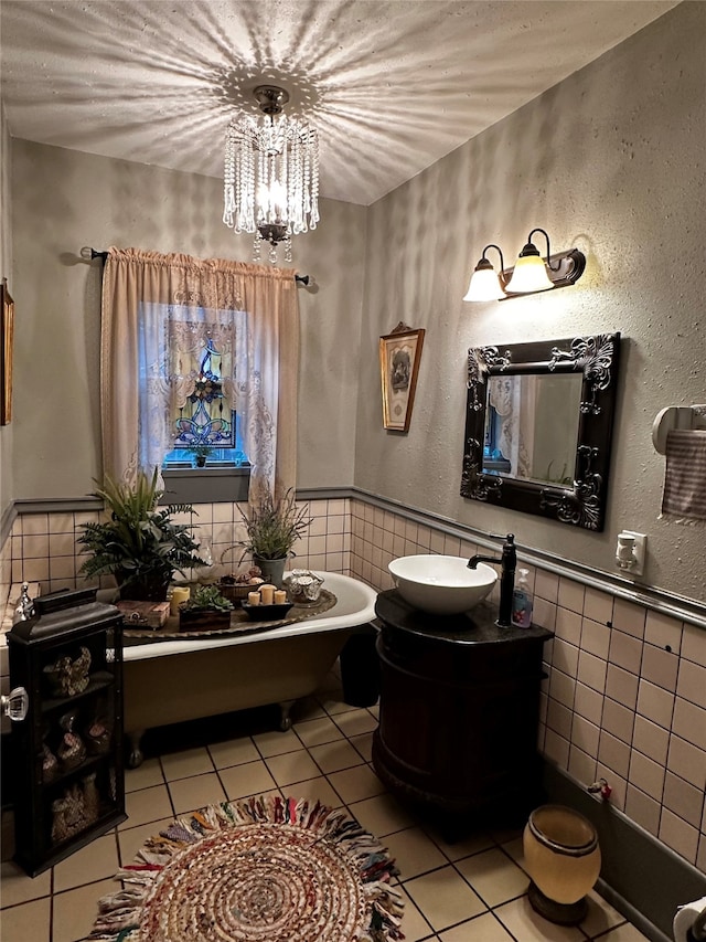 bathroom with tile patterned flooring, vanity, a notable chandelier, a bathtub, and tile walls