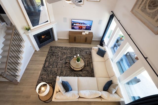 living room featuring a high ceiling, a tile fireplace, hardwood / wood-style flooring, and ceiling fan