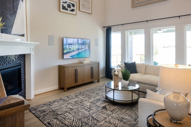 living room with a tiled fireplace and light hardwood / wood-style flooring