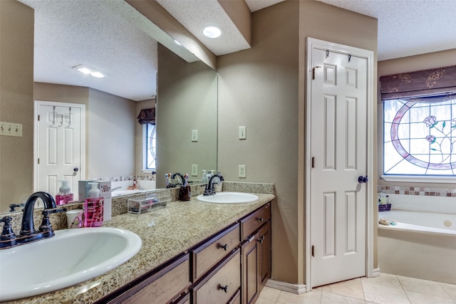 bathroom with tile patterned flooring, a washtub, a textured ceiling, and vanity