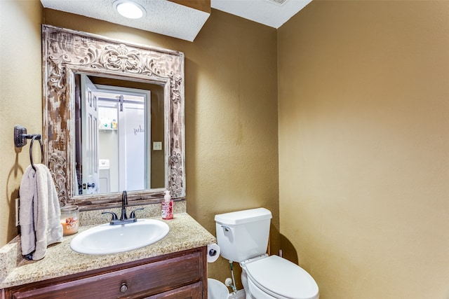 bathroom with vanity, a textured ceiling, and toilet