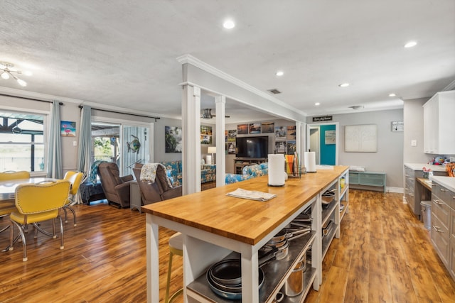 kitchen with ornamental molding, white cabinetry, ornate columns, wood counters, and light hardwood / wood-style flooring