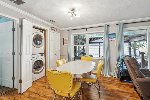 dining space featuring hardwood / wood-style floors, a textured ceiling, stacked washer / dryer, and ornamental molding