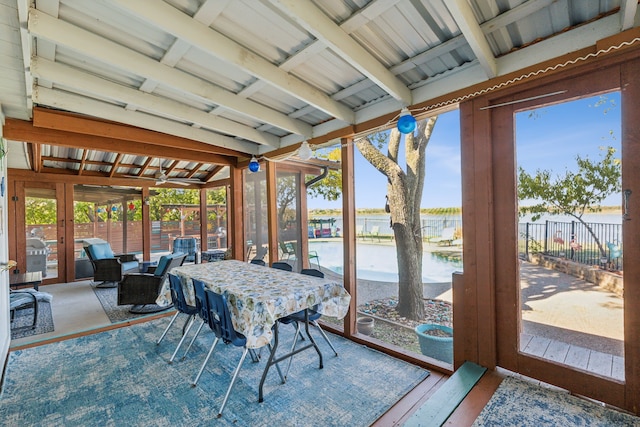 sunroom / solarium with a water view, a healthy amount of sunlight, and vaulted ceiling