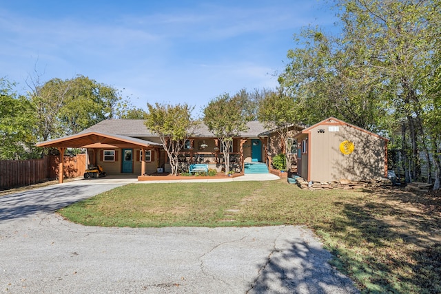 single story home with a front lawn, a storage unit, and a carport