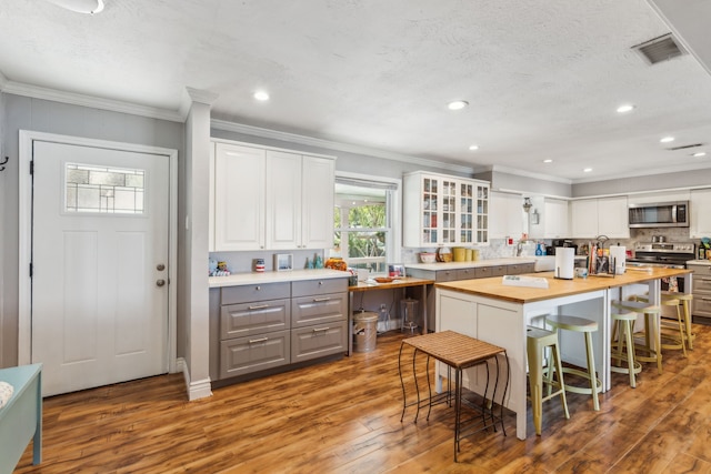 kitchen with white cabinets, stainless steel appliances, light hardwood / wood-style flooring, and wood counters