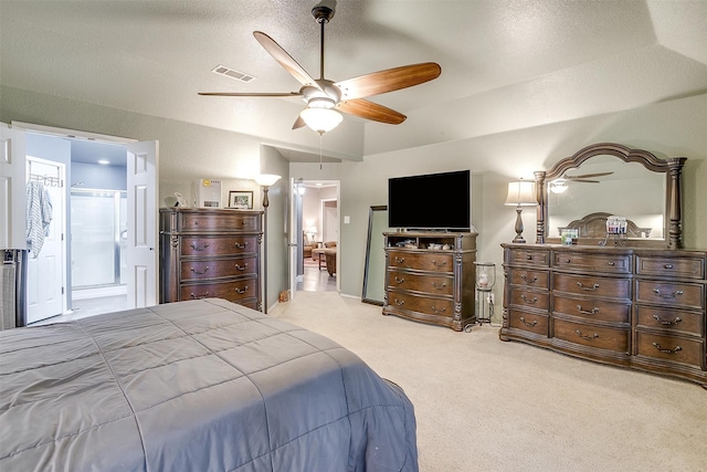 bedroom featuring a textured ceiling, light colored carpet, ensuite bath, and ceiling fan