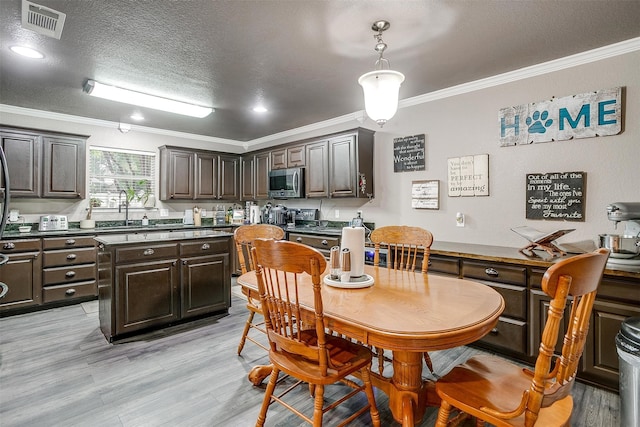 dining room with sink, light hardwood / wood-style flooring, a textured ceiling, and ornamental molding