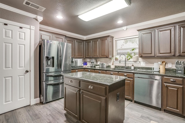 kitchen featuring sink, stainless steel appliances, crown molding, a textured ceiling, and a kitchen island