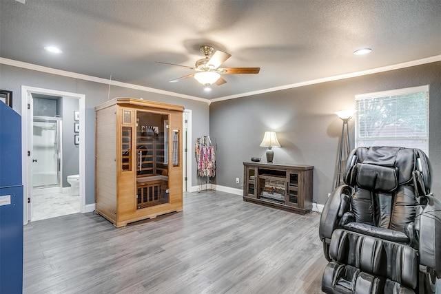 sitting room featuring ceiling fan, wood-type flooring, a textured ceiling, and ornamental molding