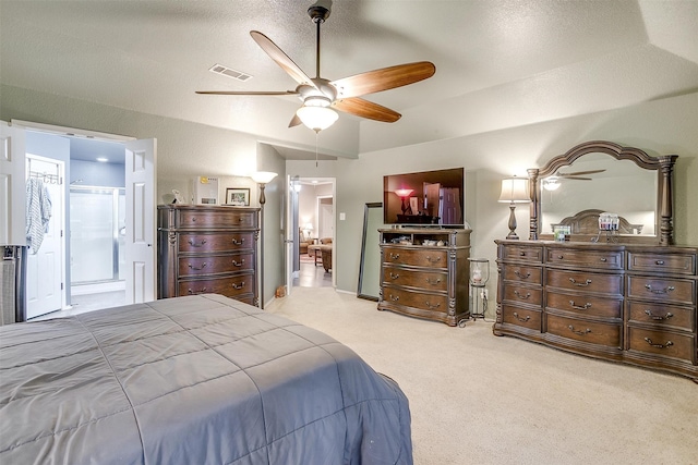 carpeted bedroom with ceiling fan, ensuite bathroom, and a textured ceiling