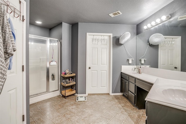 bathroom featuring a textured ceiling, vanity, tile patterned floors, and a shower with shower door