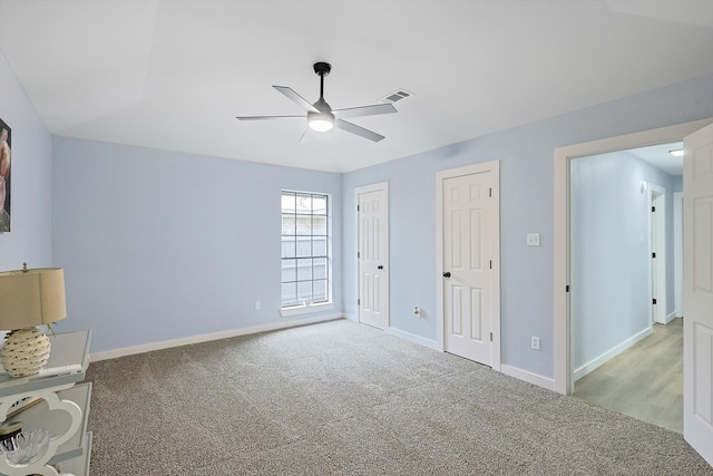 unfurnished bedroom featuring light colored carpet, ceiling fan, and two closets