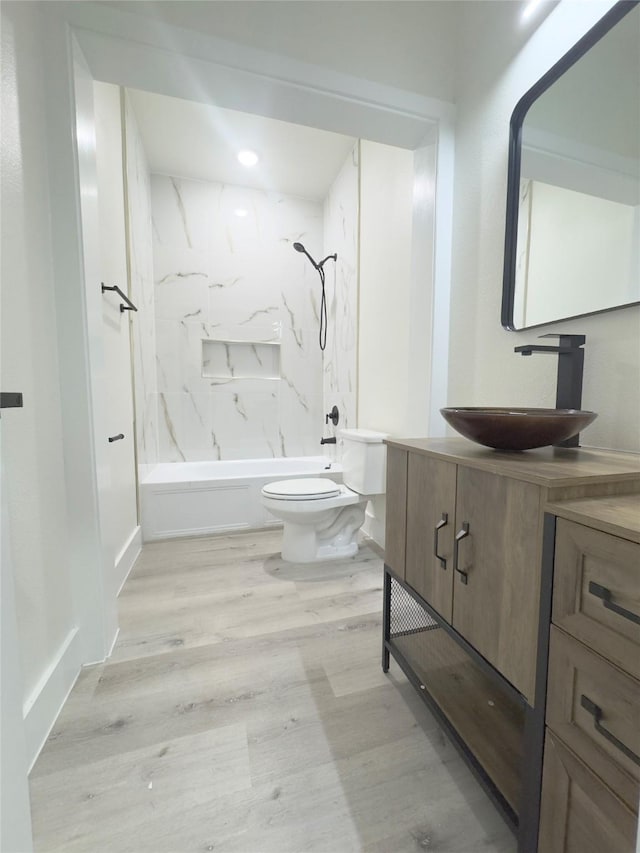 full bathroom with hardwood / wood-style floors, vanity, toilet, and tiled shower / bath combo