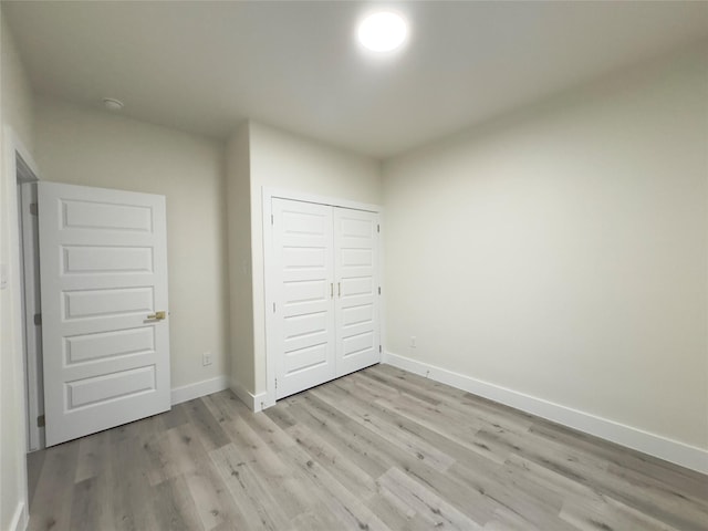 unfurnished bedroom with light wood-type flooring and a closet