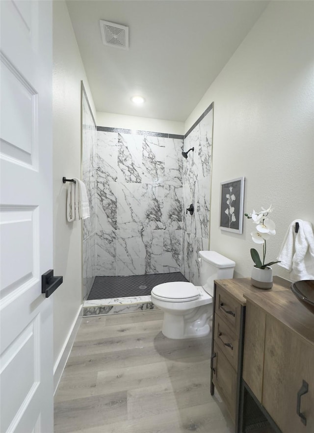 bathroom featuring a tile shower, toilet, and hardwood / wood-style floors