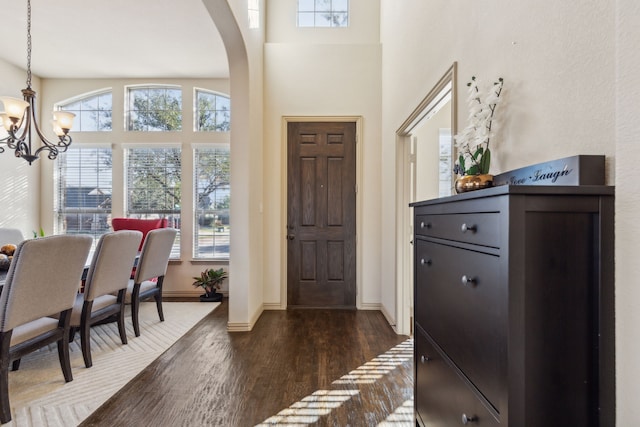 entrance foyer featuring dark hardwood / wood-style flooring, an inviting chandelier, and a towering ceiling