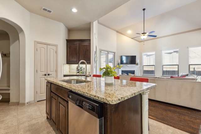 kitchen with ceiling fan, a center island with sink, stainless steel dishwasher, sink, and dark brown cabinets