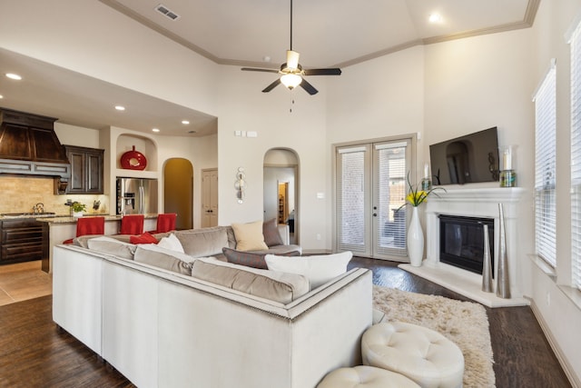 living room with ceiling fan, dark hardwood / wood-style floors, crown molding, a high ceiling, and french doors