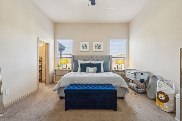 bedroom featuring light carpet, ceiling fan, and multiple windows