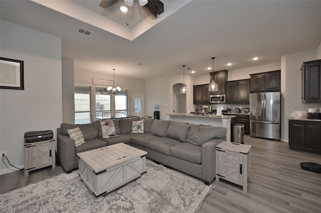 living room featuring hardwood / wood-style flooring, ceiling fan with notable chandelier, and sink