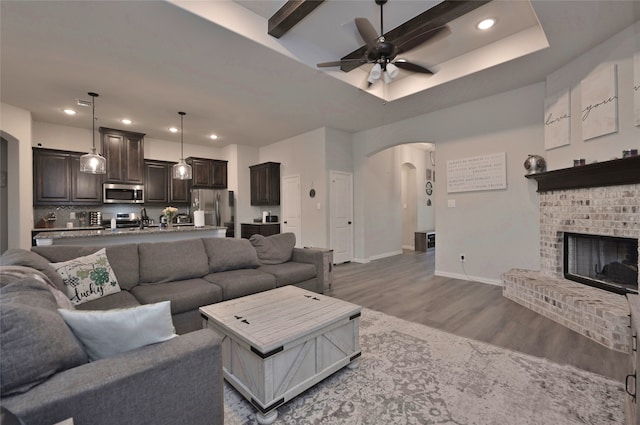 living room featuring hardwood / wood-style floors, ceiling fan, sink, and a brick fireplace