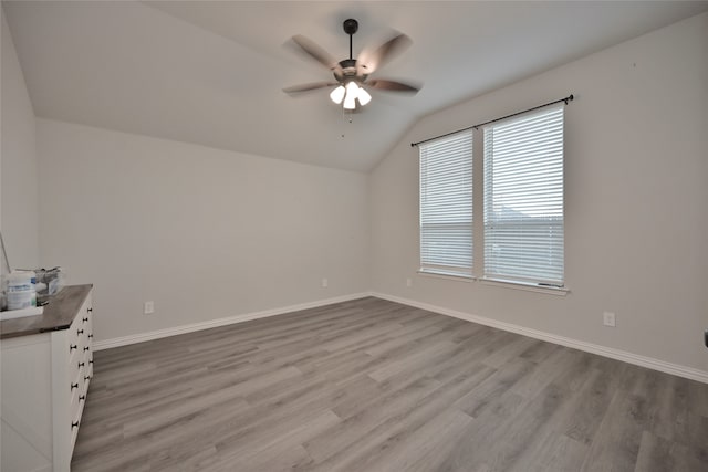 empty room with light wood-type flooring, ceiling fan, and vaulted ceiling