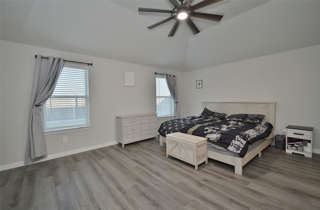 bedroom featuring hardwood / wood-style flooring, multiple windows, ceiling fan, and vaulted ceiling