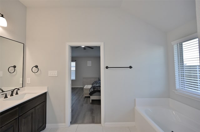 bathroom with vanity, a tub to relax in, lofted ceiling, and tile patterned flooring