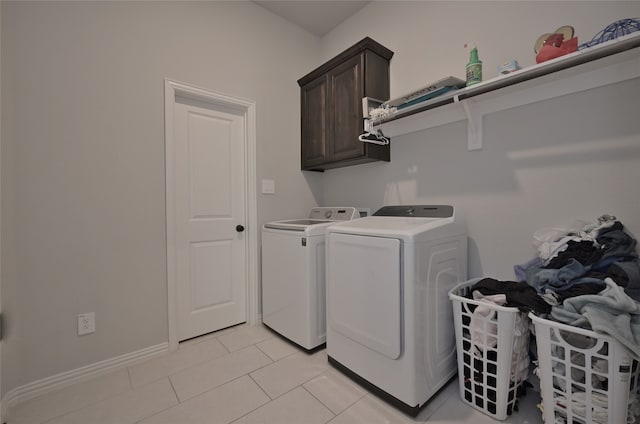 washroom featuring cabinets, washing machine and dryer, and light tile patterned floors