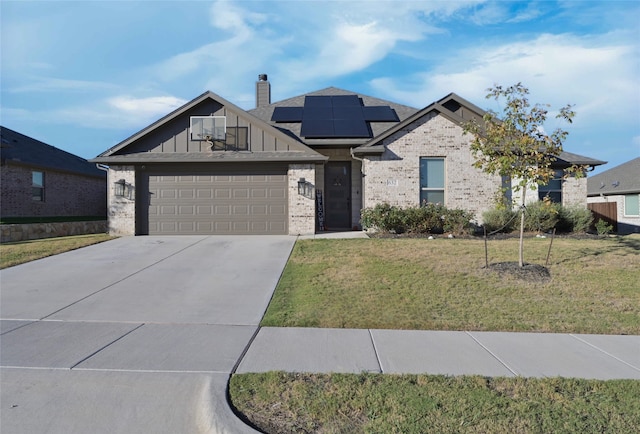 view of front facade featuring a garage, solar panels, and a front lawn