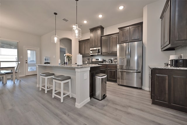 kitchen with pendant lighting, an island with sink, light hardwood / wood-style floors, and stainless steel appliances