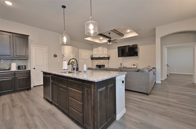 kitchen with dishwasher, light hardwood / wood-style floors, sink, and an island with sink