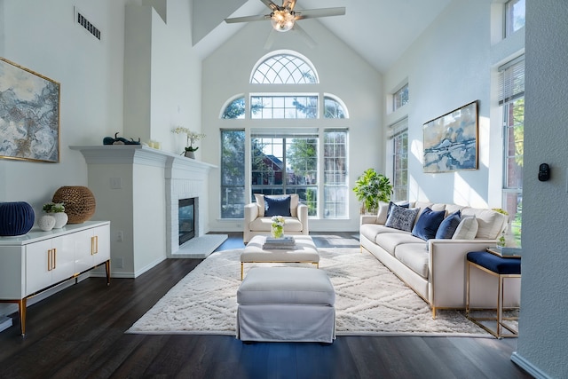 living room featuring a fireplace, a healthy amount of sunlight, high vaulted ceiling, and dark wood-type flooring