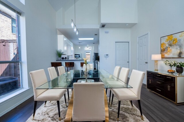 dining area featuring wood-type flooring and a high ceiling