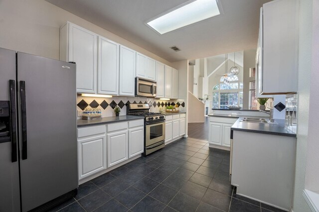 kitchen with white cabinetry, sink, stainless steel appliances, backsplash, and decorative light fixtures