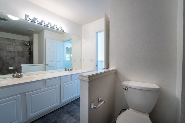 bathroom featuring tiled shower, tile patterned floors, vanity, and toilet