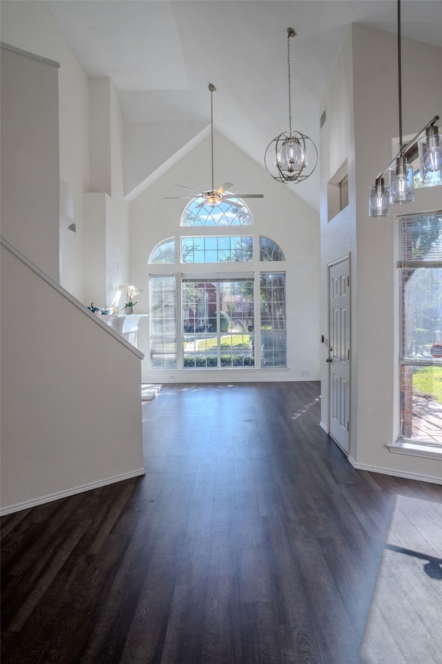 entryway with ceiling fan with notable chandelier, high vaulted ceiling, a wealth of natural light, and dark wood-type flooring