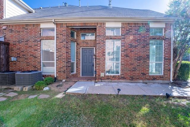 doorway to property featuring a patio, central AC, and a lawn