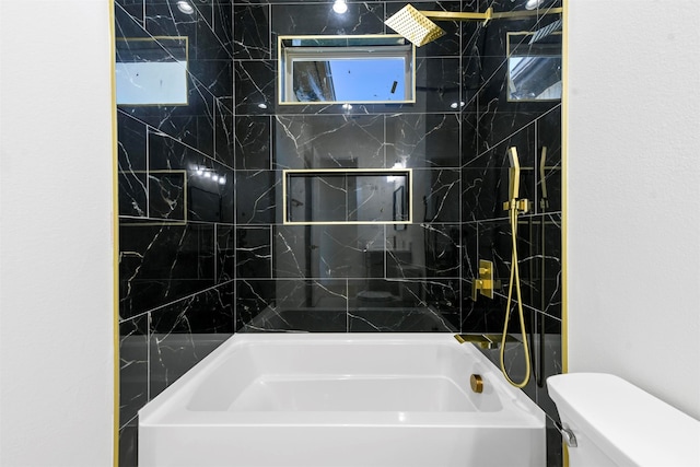 bathroom featuring toilet and tiled shower / bath combo