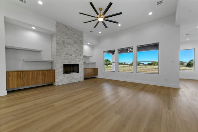 unfurnished living room with a fireplace, ceiling fan, a healthy amount of sunlight, and light wood-type flooring