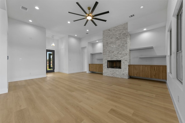 unfurnished living room with a stone fireplace, light hardwood / wood-style floors, and ceiling fan