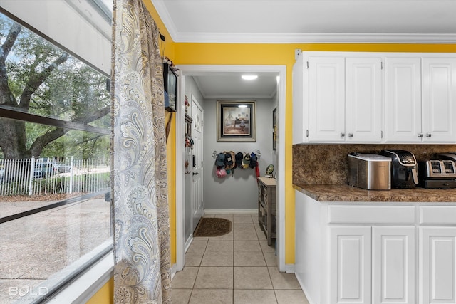 kitchen with decorative backsplash, white cabinetry, crown molding, and light tile patterned floors