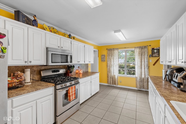 kitchen featuring decorative backsplash, appliances with stainless steel finishes, ornamental molding, white cabinetry, and light tile patterned flooring