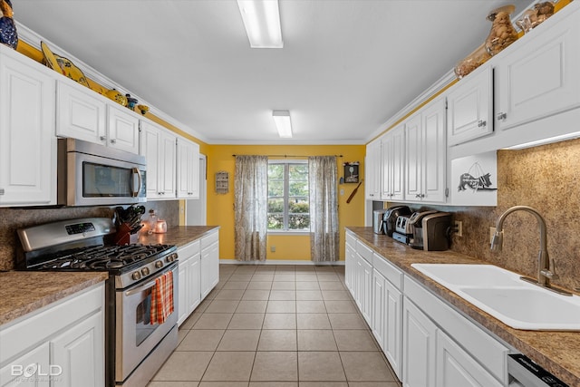 kitchen featuring white cabinets, ornamental molding, sink, and appliances with stainless steel finishes